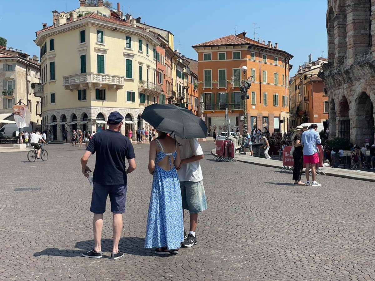 Turisti si riparano dal caldo con un ombrello in piazza Bra a Verona