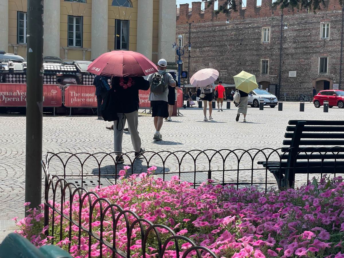 Turisti si riparano dal caldo con un ombrello in piazza Bra a Verona